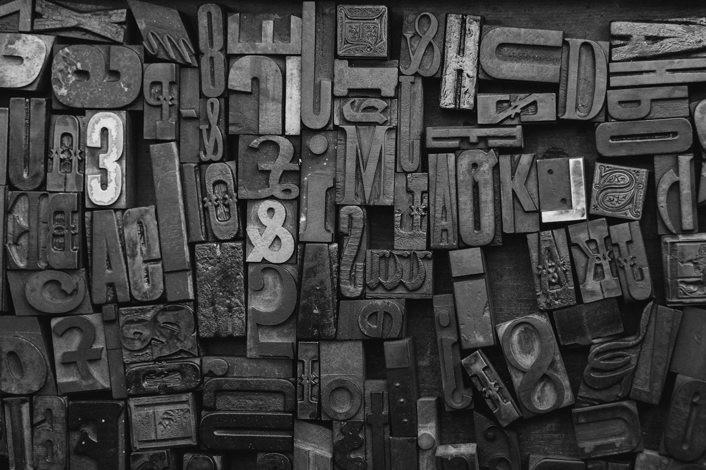 A wall of worn wooden letterpress type blocks