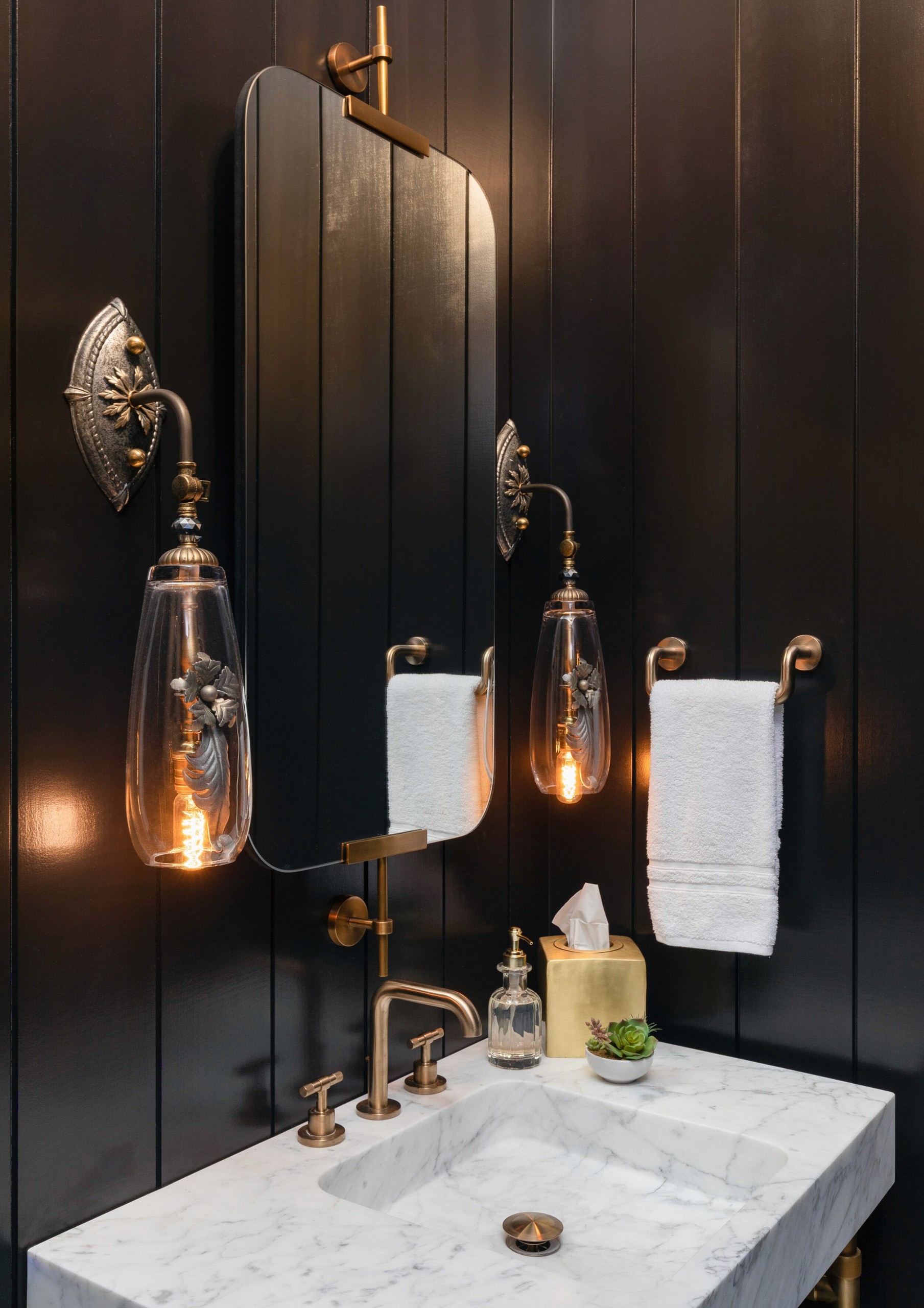Marble sink with brass faucet and decorative sconces.