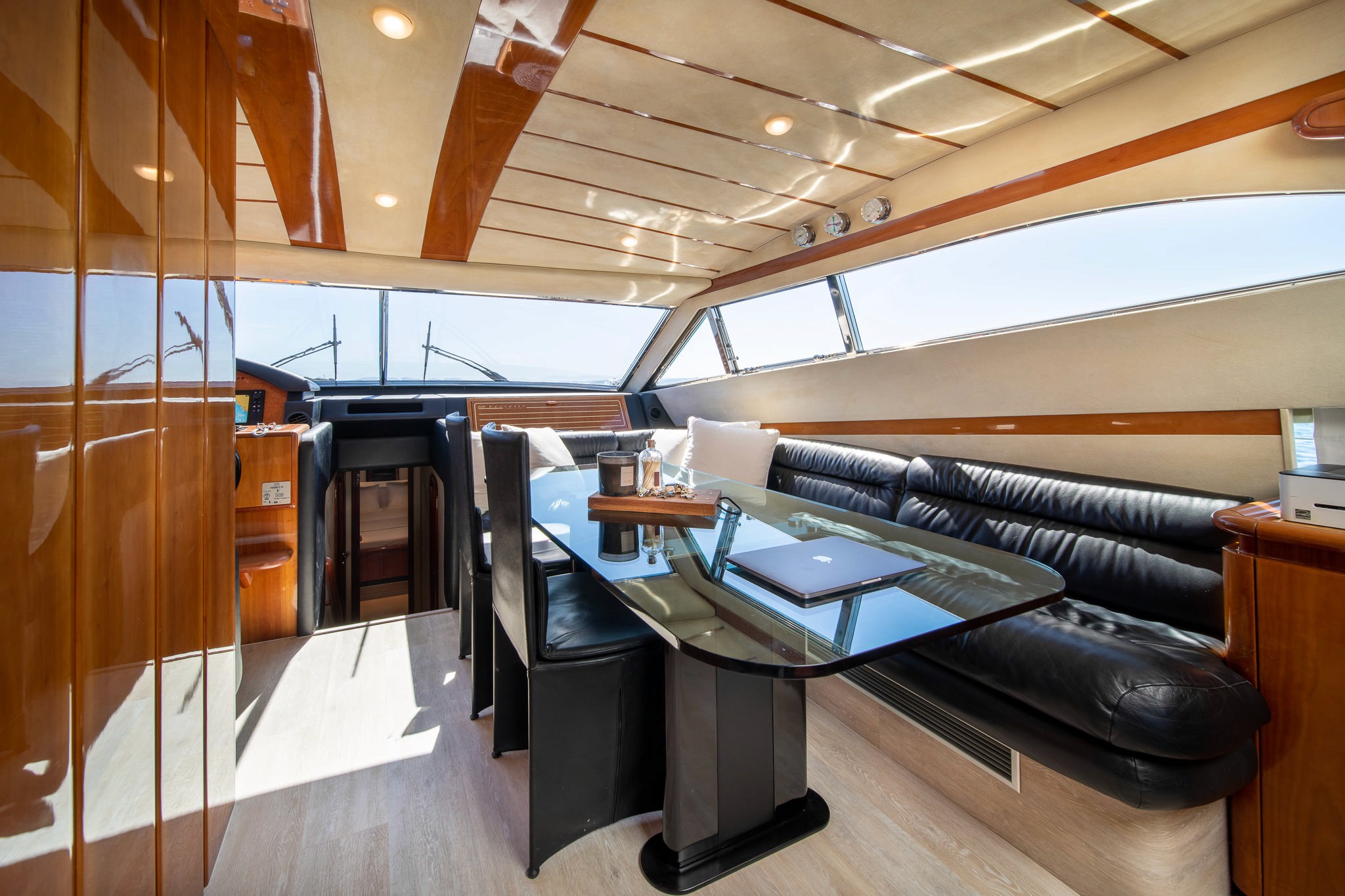 Luxurious interior salon of Ferretti 68 yacht featuring black leather seating, glass dining table, and panoramic windows with ocean views.