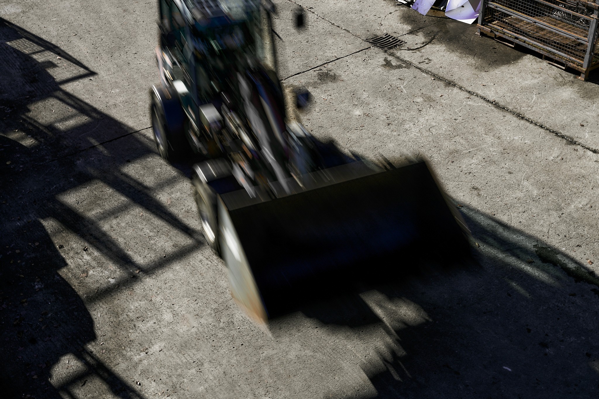 Ein Radlader in Bewegung, mit angehobener Schaufel. Schatten.