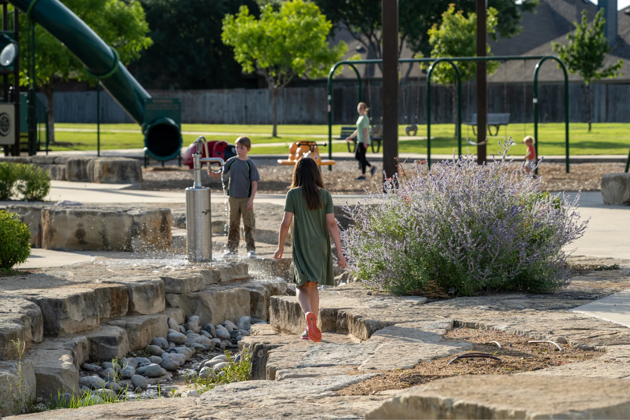 Children exploring natural stone terracing and native flowering plants at a civic park designed by East Fork Landscape Architecture Lab