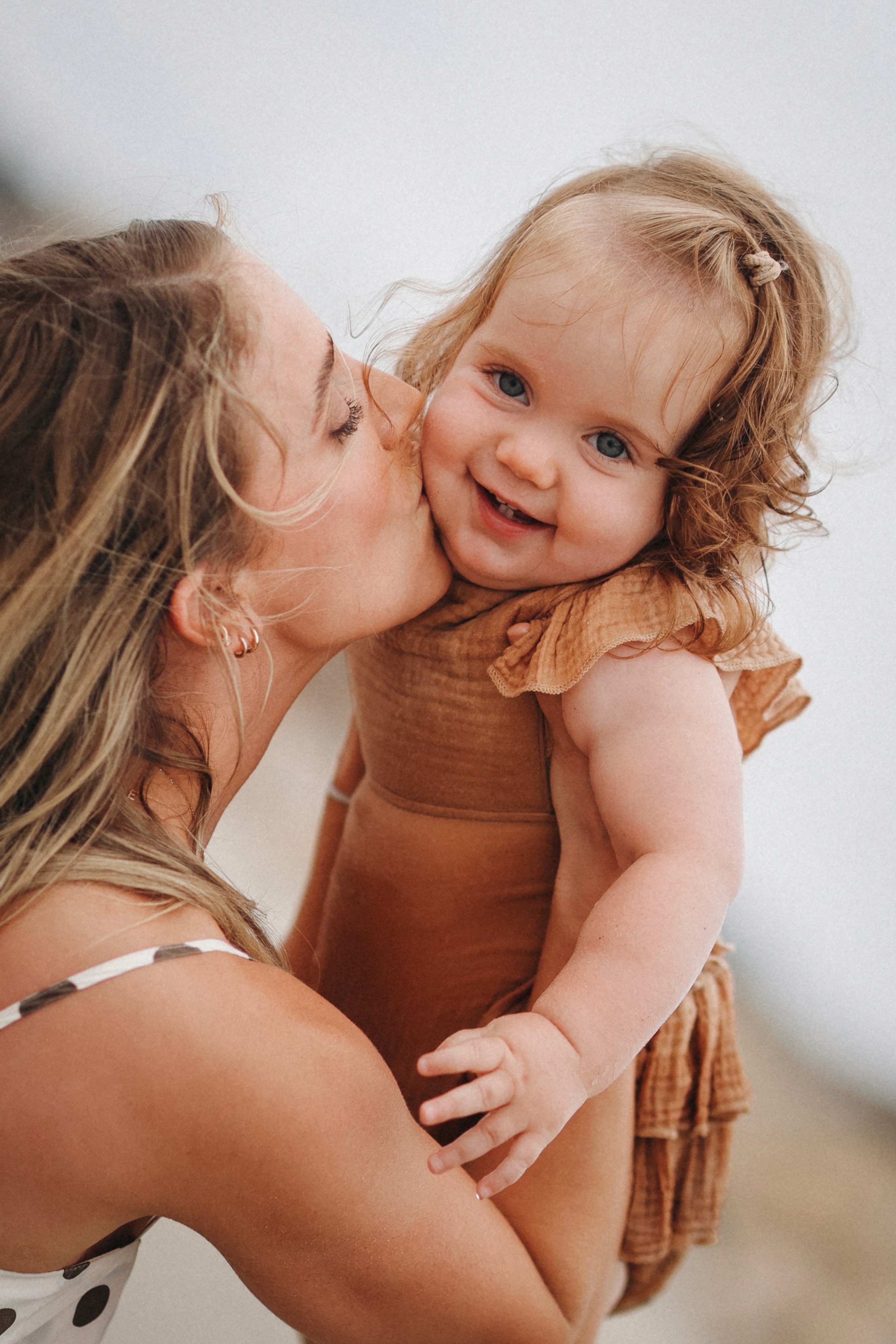 Mother holding her laughing toddler daughter during a warm sunset moment