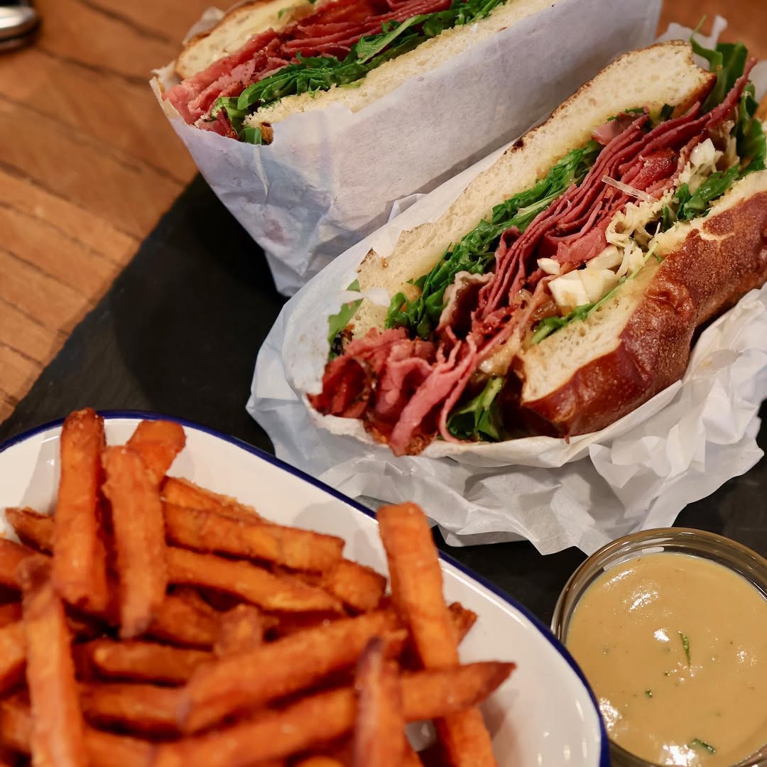 Deftiges Sandwich mit Rindfleisch, frischem Grün und Sauce, serviert mit knusprigen Pommes und Dip im kAlps.