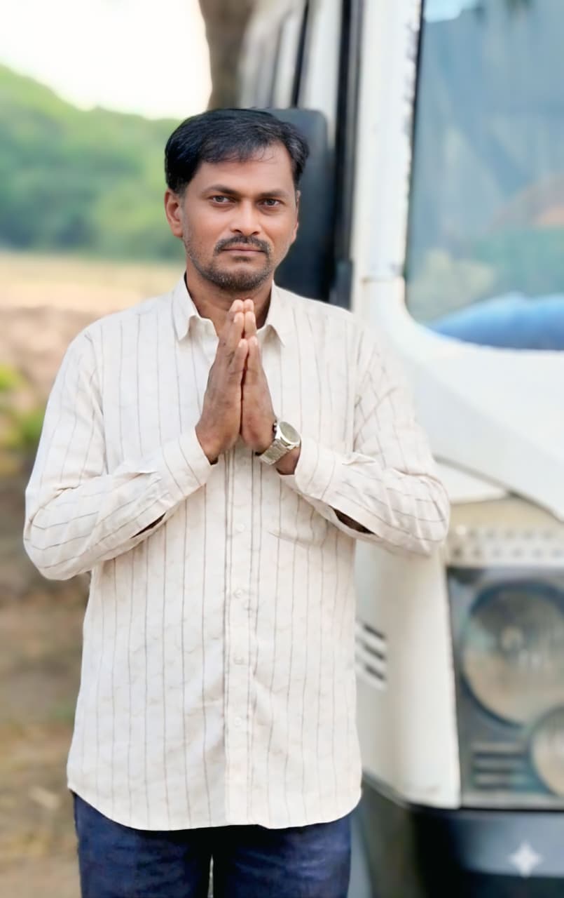 Smiling female therapist with short gray hair, wearing a brown top and a purple shawl, surrounded by a cozy background.