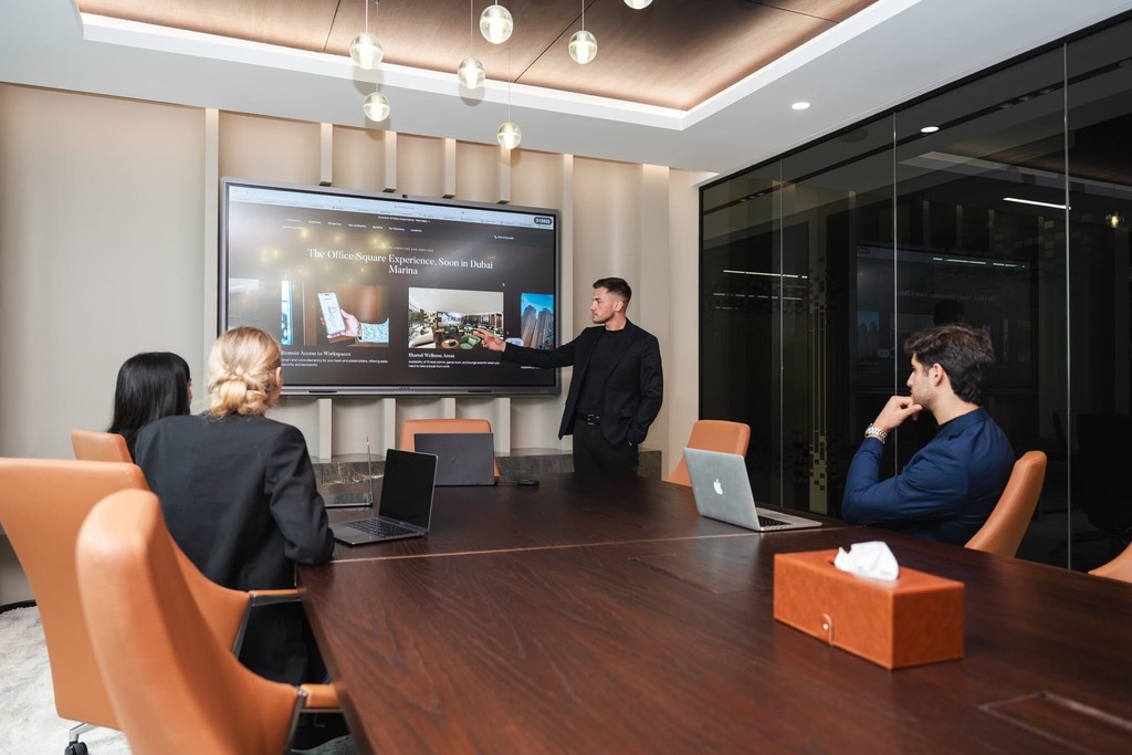Shared lounge and pantry area with green seating, open coffee station, and a blend of social and workspaces.