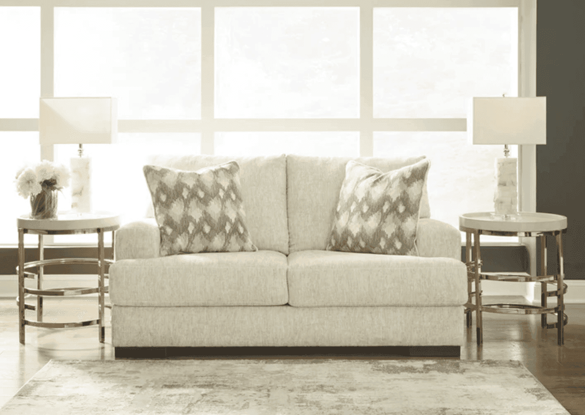 Ashley Caretti sofa in a light beige tone, paired with matching pillows and elegant side tables