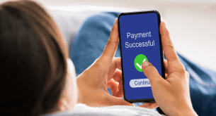 A person holding a cell phone with a “Payment Successful” message on the screen.