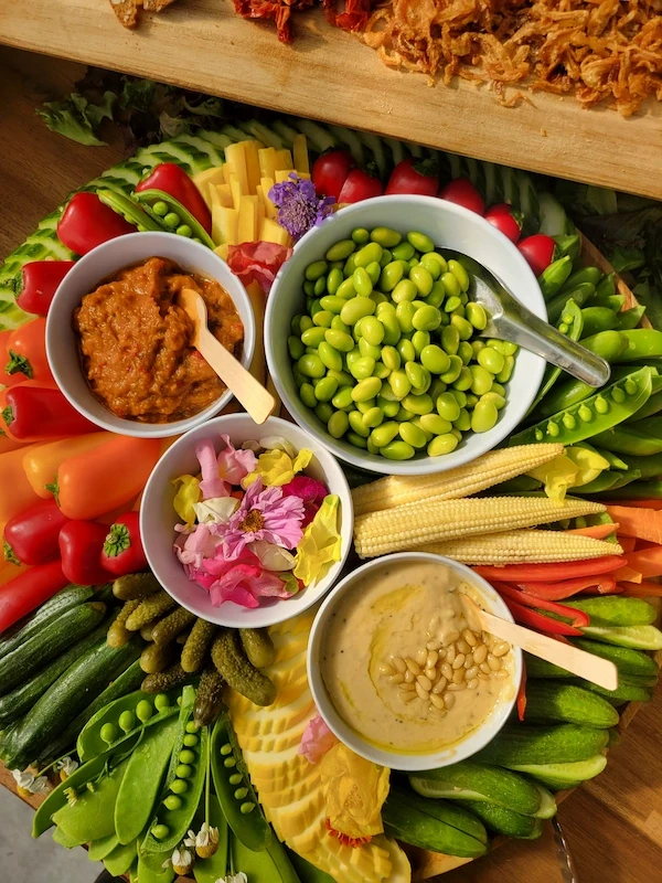 Fresh vegetable catering platter with edamame, peppers, and hummus