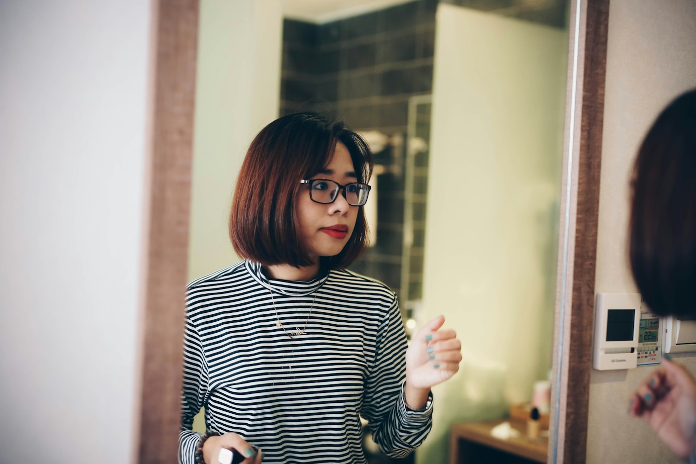 Woman with a bob haircut wearing round glasses in a softly lit room