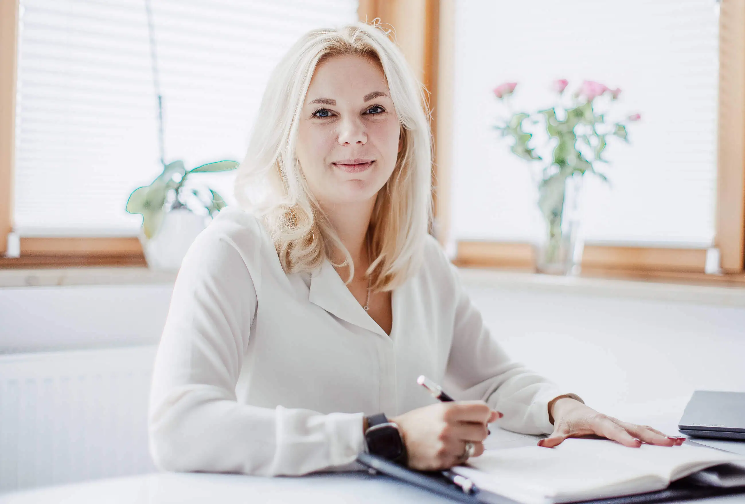 Theresa an ihrem Schreibtisch bei der Arbeit an HR-Copywriting-Strategie, umgeben von Pflanzen in einem hellen professionellen Workspace