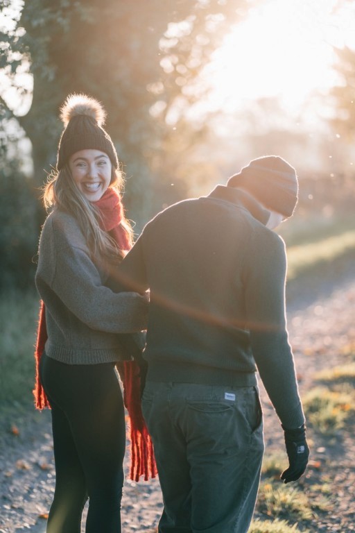 A couple walking away from us down a countrylane in golden hour.