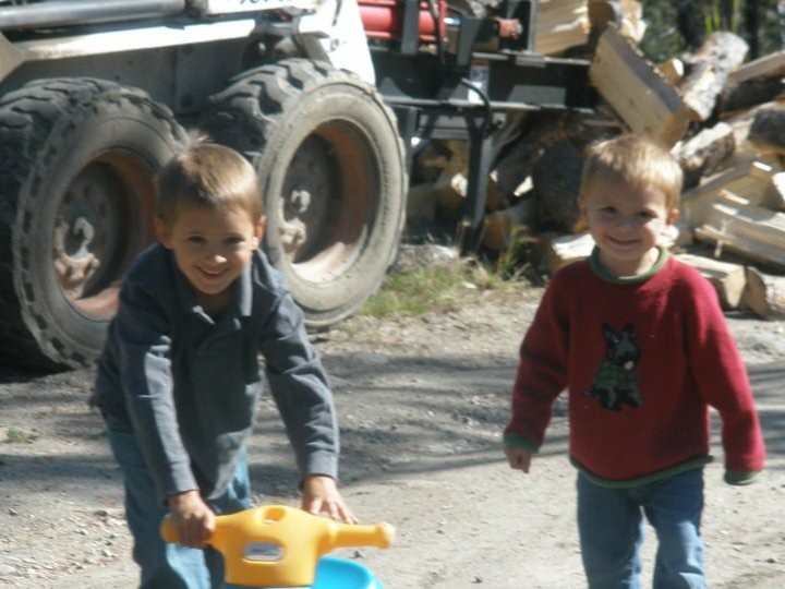 Two young boys playing outside beside large vehicle tires