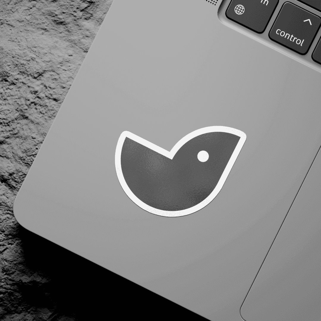 Black-and-white close-up of a laptop palm rest with a die-cut bird-shape logo sticker applied