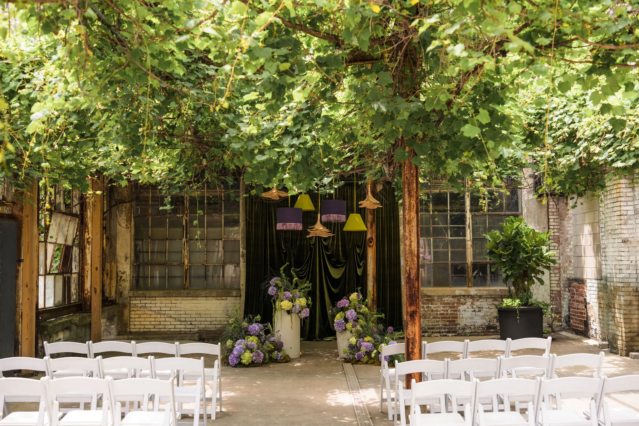 Strongwater courtyard under an ivy canopy set with white chairs for a ceremony