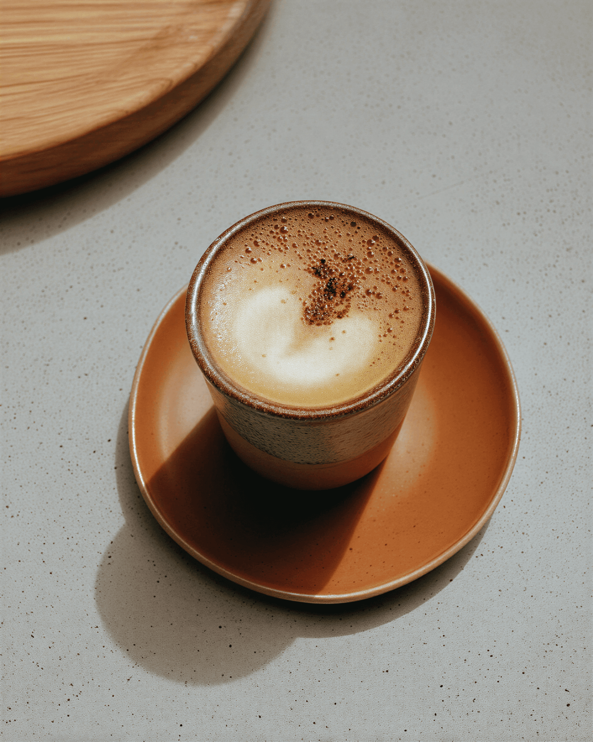 Freshly made cappuccino with latte art in a ceramic bowl on a wooden tray