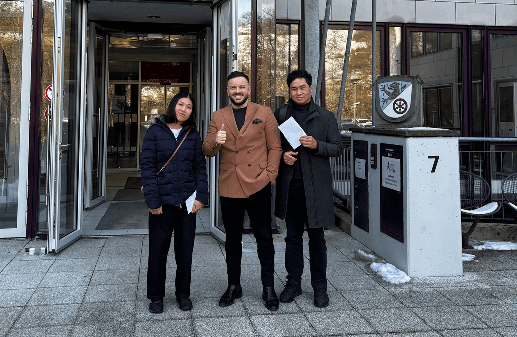 Ben Wassermann von workiOn mit zwei vermittelten Fachkräften vor dem Eingang einer deutschen Ausländerbehörde.