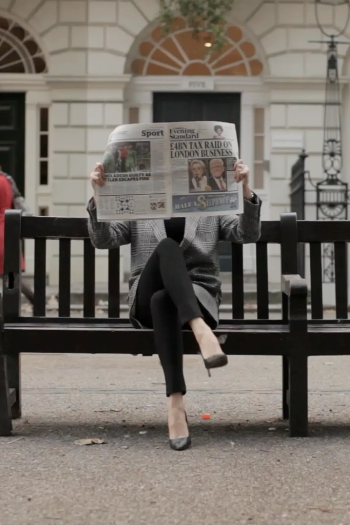 Elena sitting on a bench outside Guy Ritchie’s London apartment holding a newspaper during the documentary filming