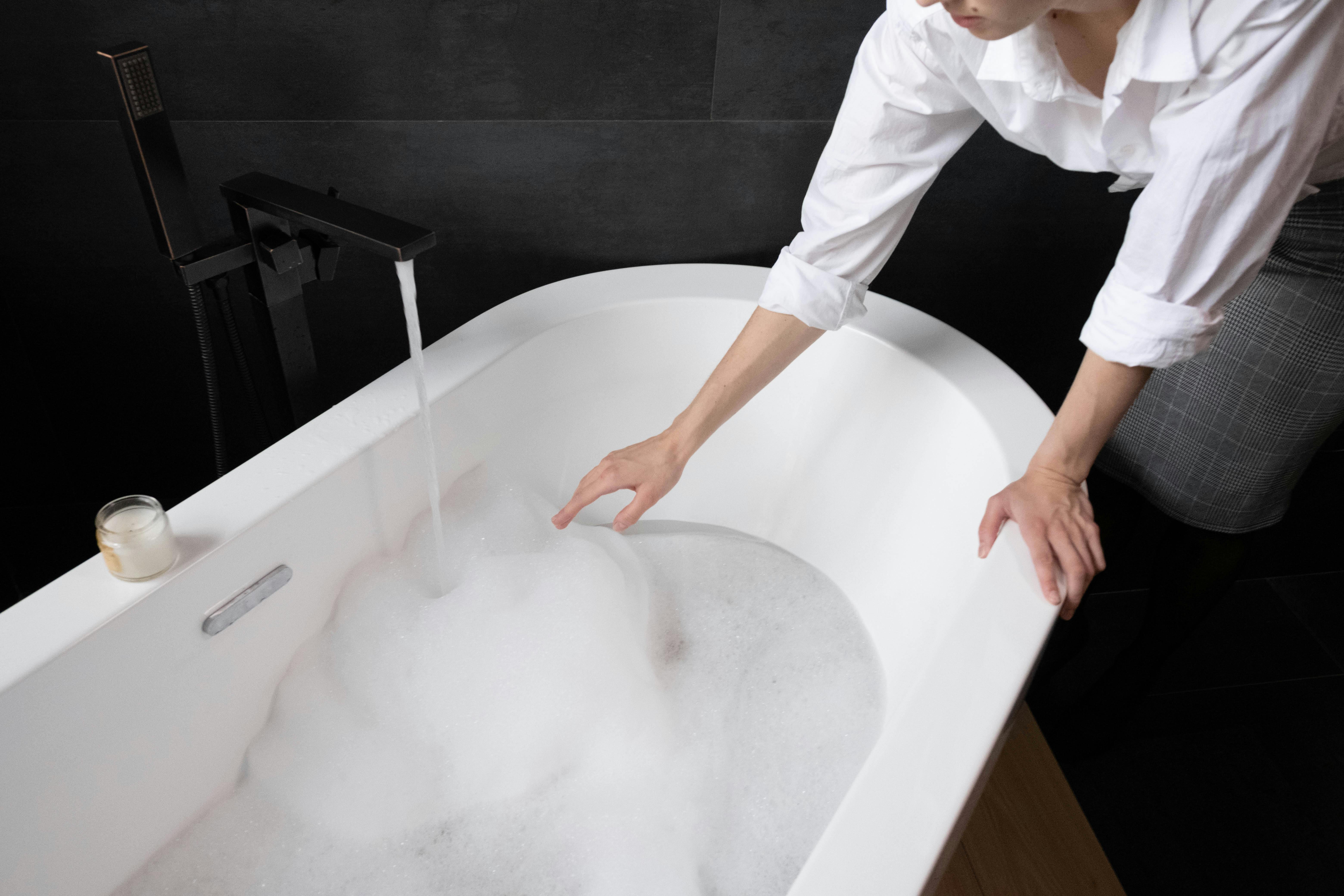 Woman filling a bath with hot water, how to choose a water heater, water heater replacement, water heater installation, water heater replacement near me, water heater installation near me.