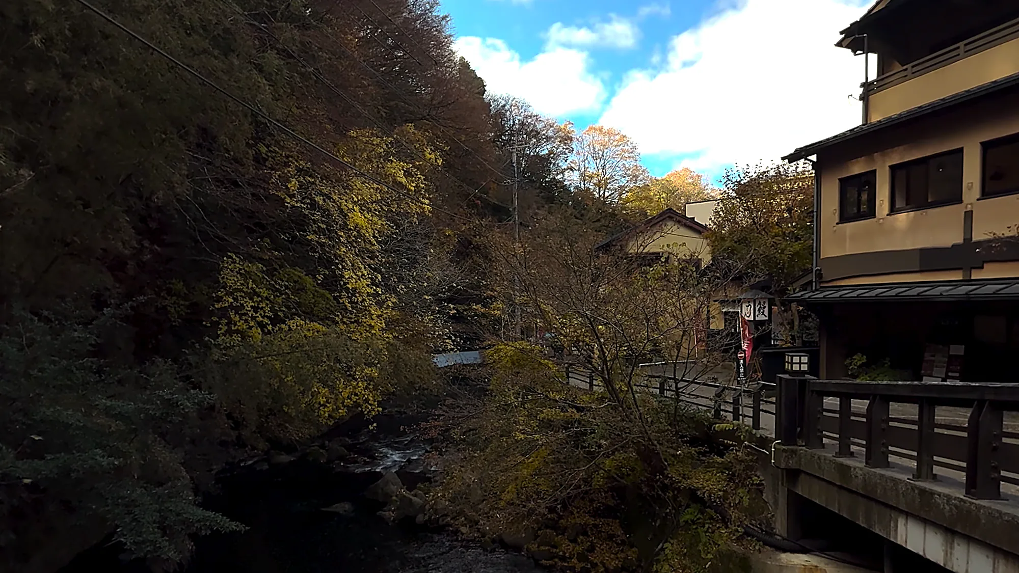 A timber inn standing above the gorge at Kurokawa Onsen beside a bridge