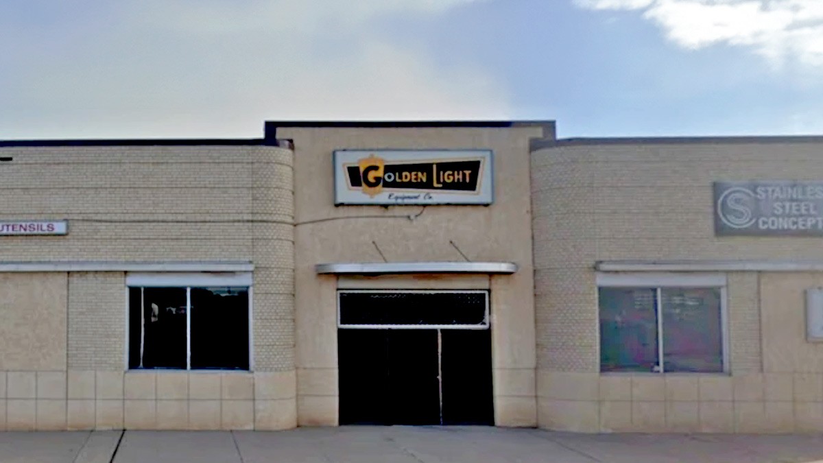 Facade of a commercial building with large windows and a flat roof under a cloudy sky.