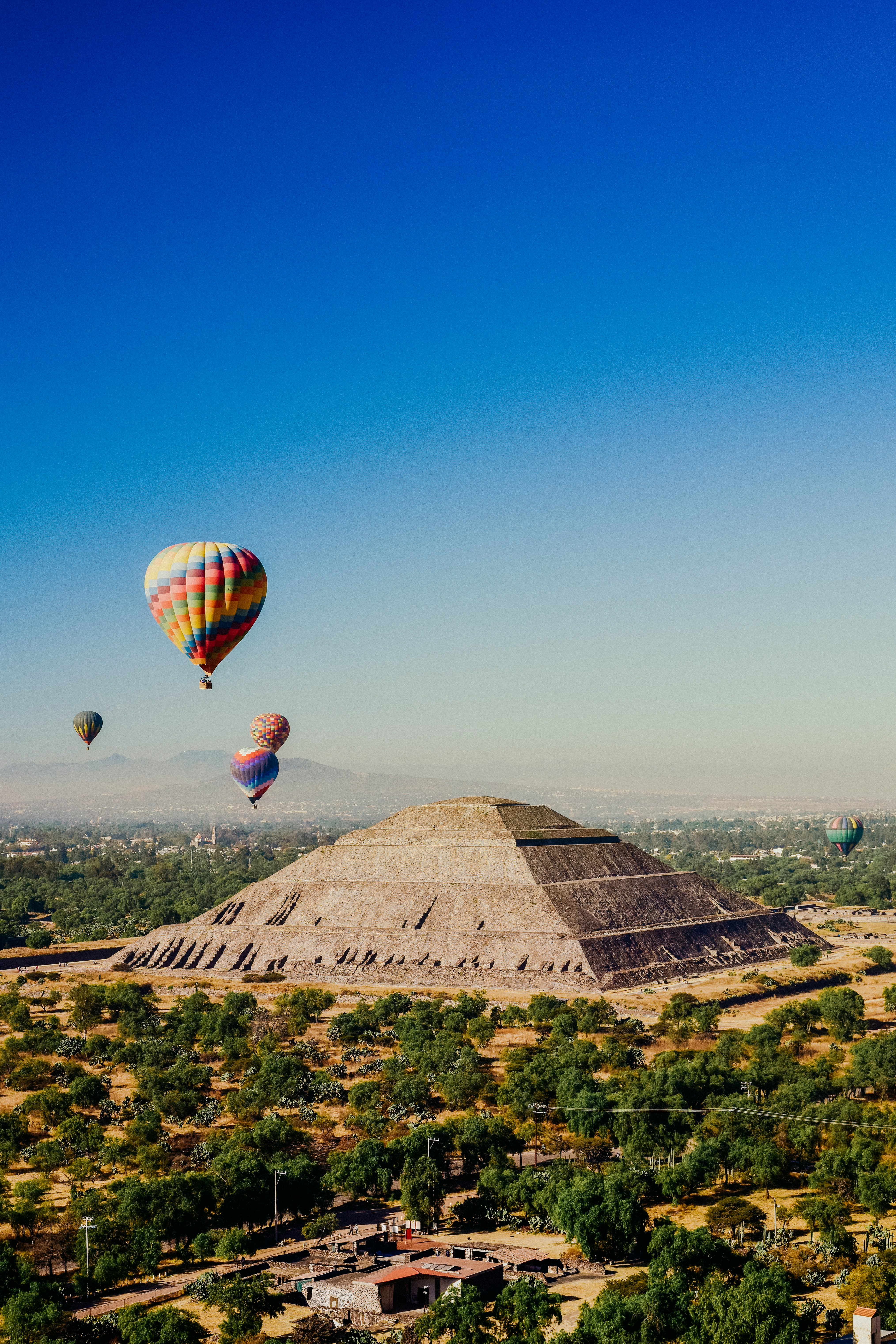 a group of hot air balloons flying over a pyramid