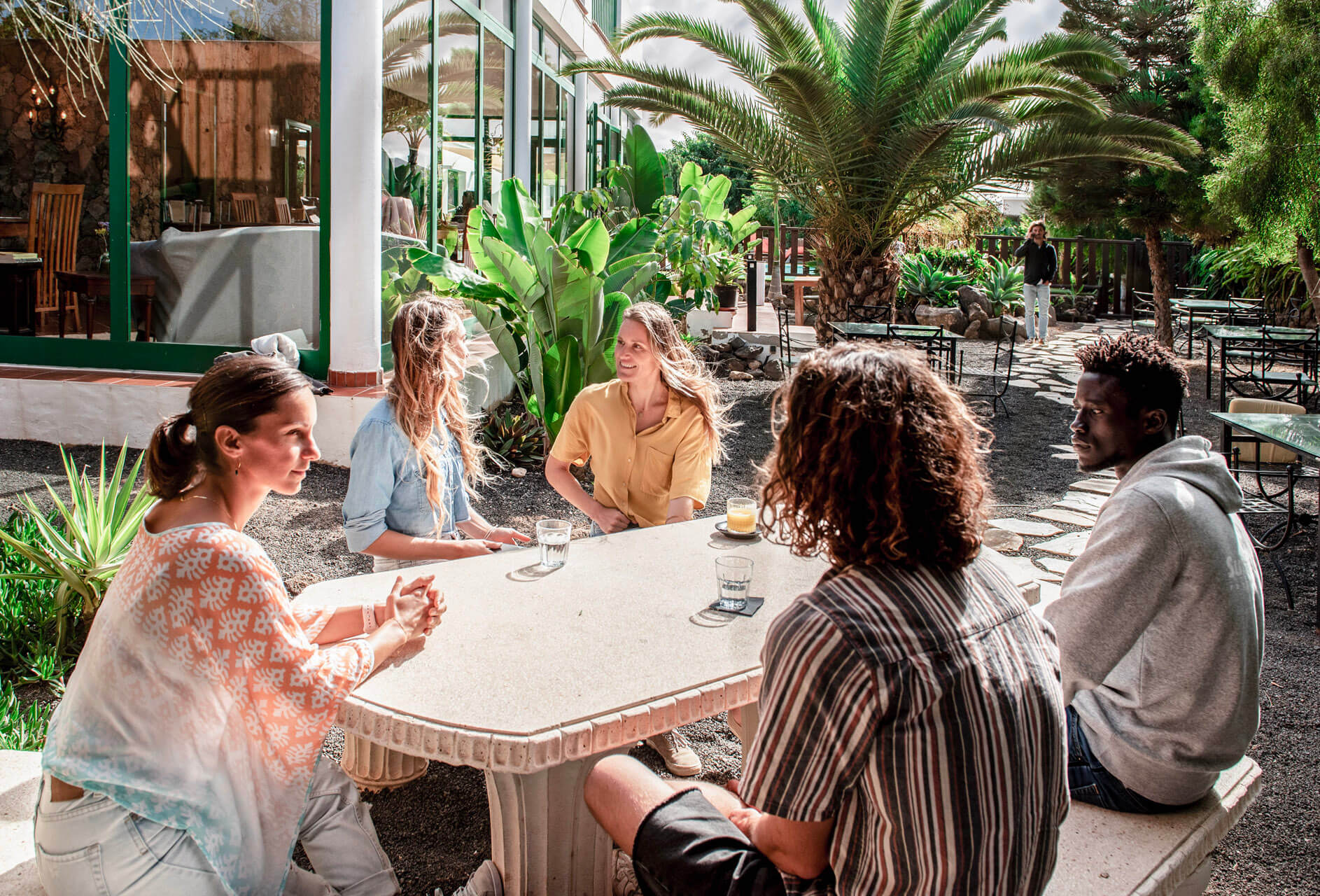 Cinco personas se reúnen en una mesa de terraza.