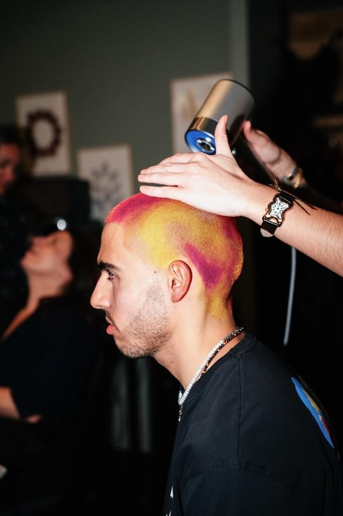 Coiffeur réalisant une coloration rose et jaune sur un client dans un salon ECLA Group