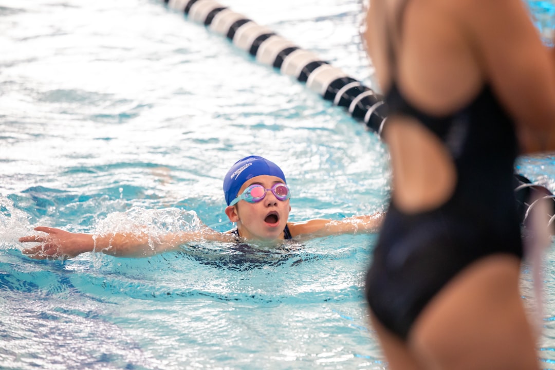 a young girl swimming in a pool wearing a swimming cap