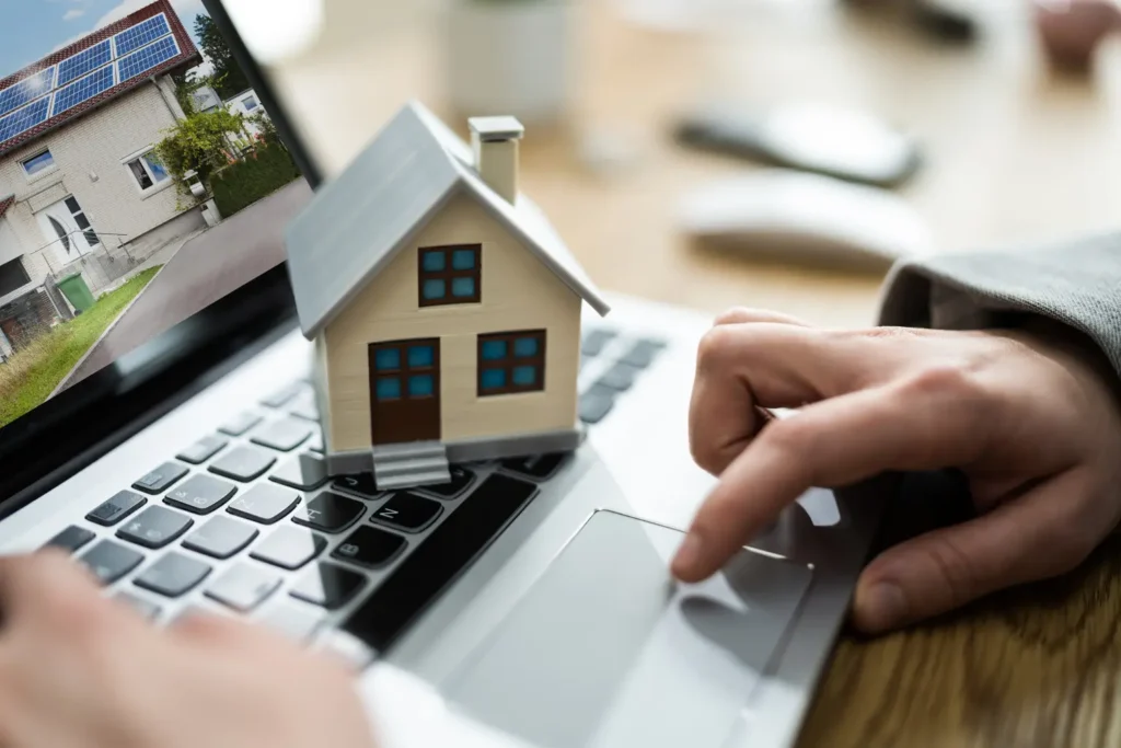 Property management software for landlords represented by a miniature house on a laptop keyboard.