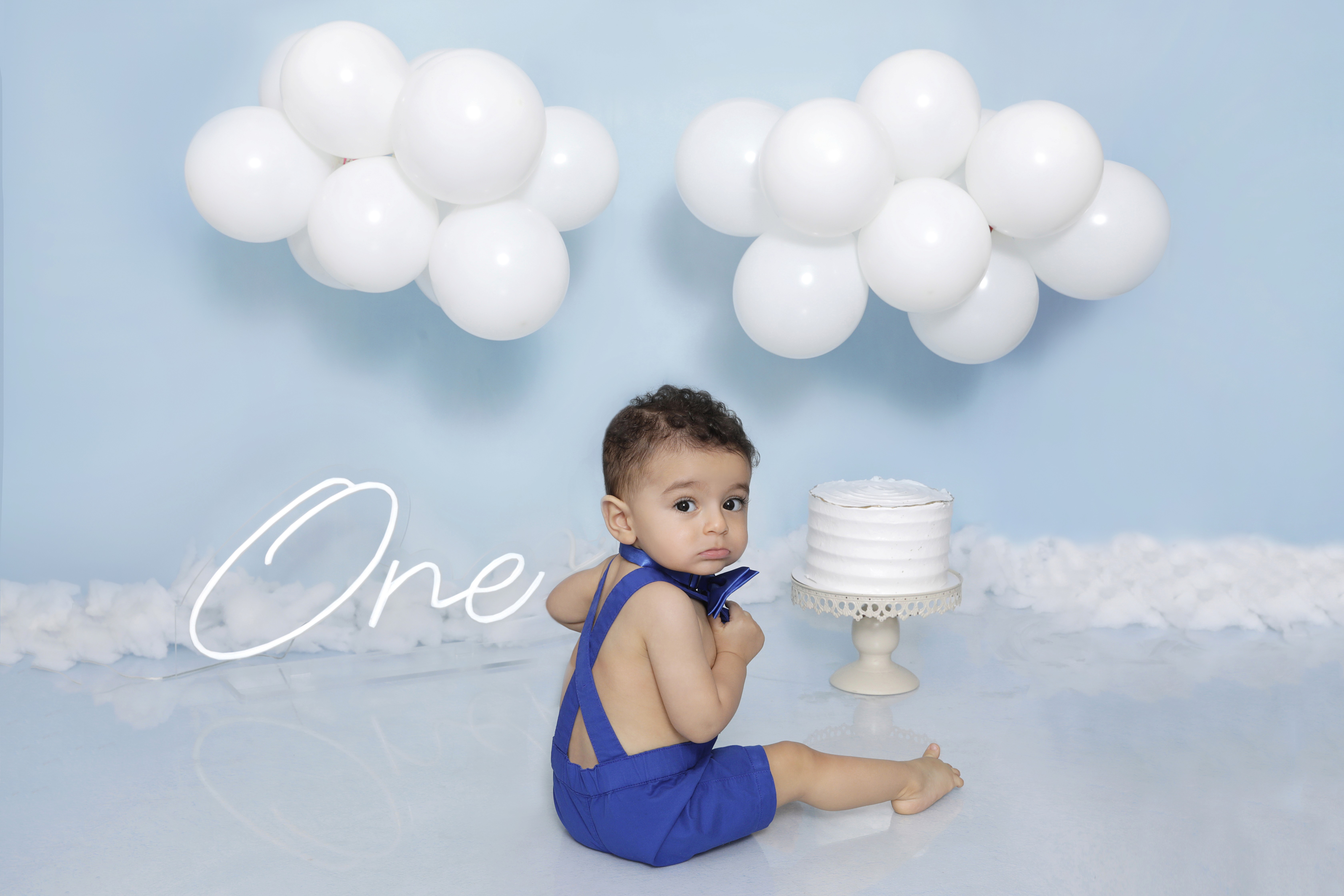 Capturing baby's first year: A blue-themed cake smash session with professional studio lighting and festive styling.