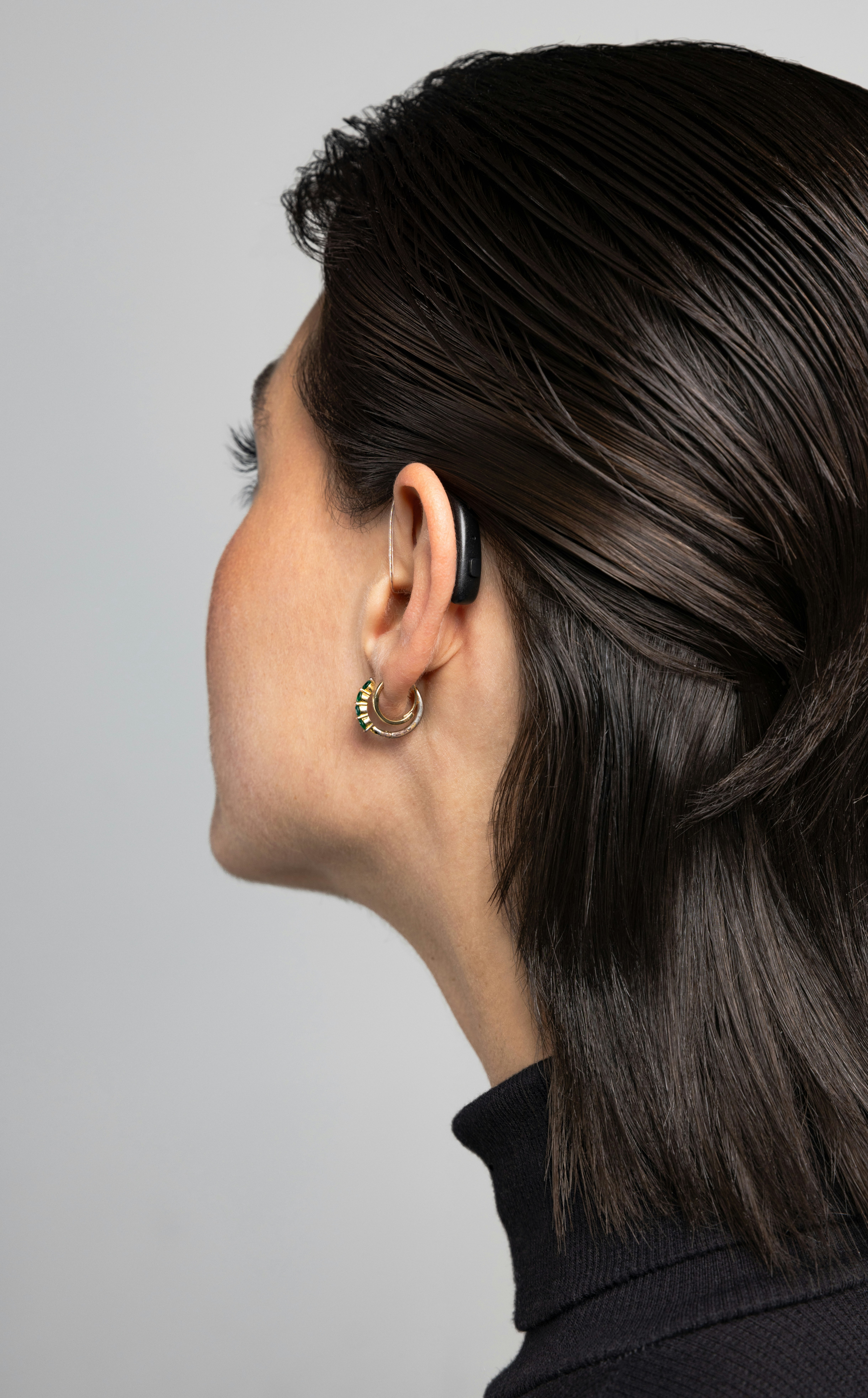 Audífono recargable colocado en la oreja de una mujer, diseñado para un día completo de autonomía sin pilas