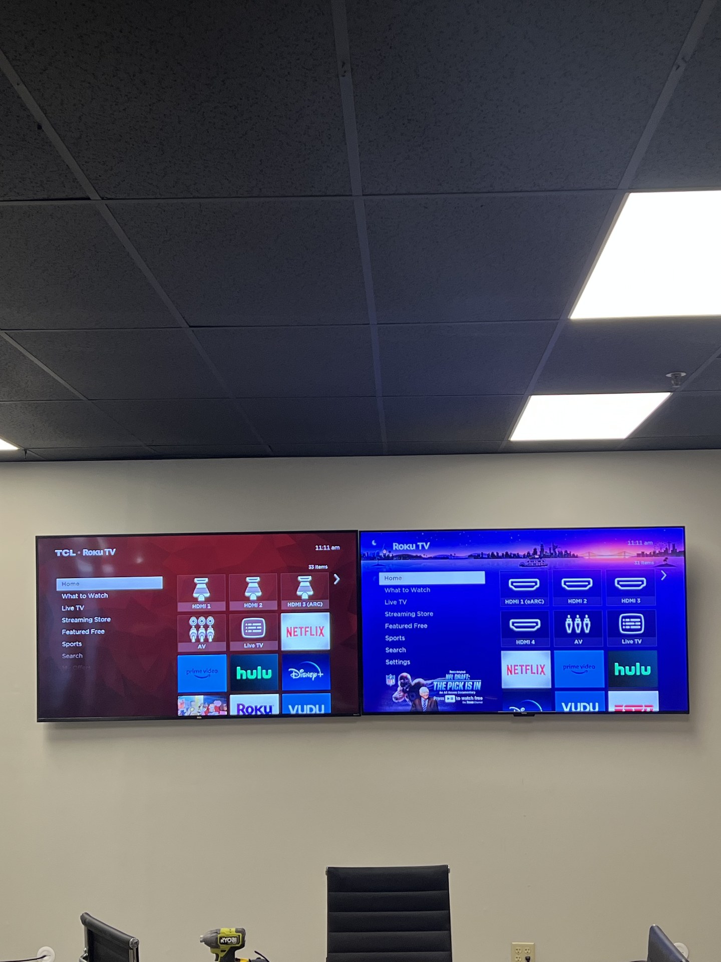 Both side-by-side televisions switched on and aligned above the workspace