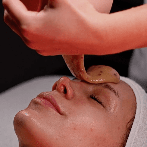 Close-up of a woman applying serum drops onto her hand using a dropper bottle