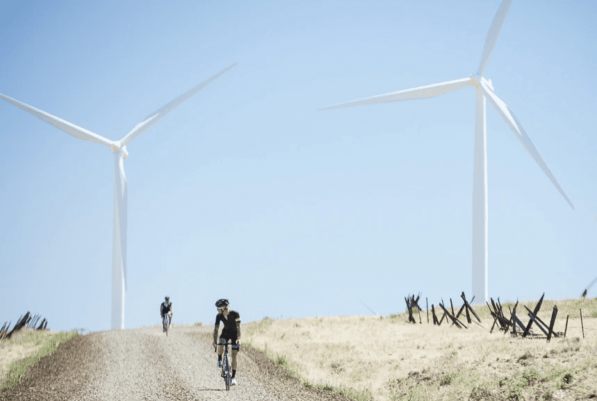 Cyclists passing distant windmills