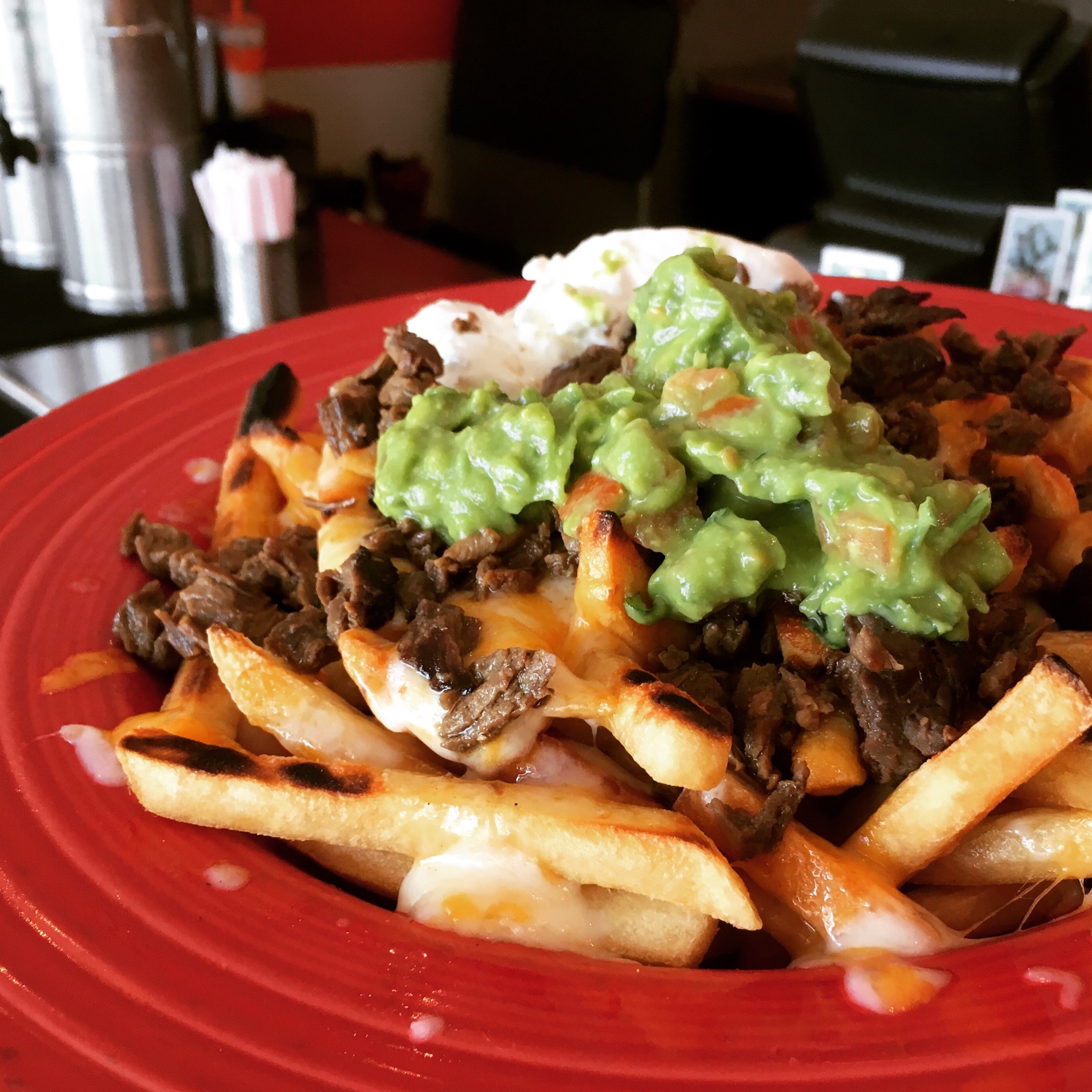 Golden carne asada fries topped with tender marinated steak, melted cheese, guacamole, and sour cream—Taco Spot LA’s signature dish.