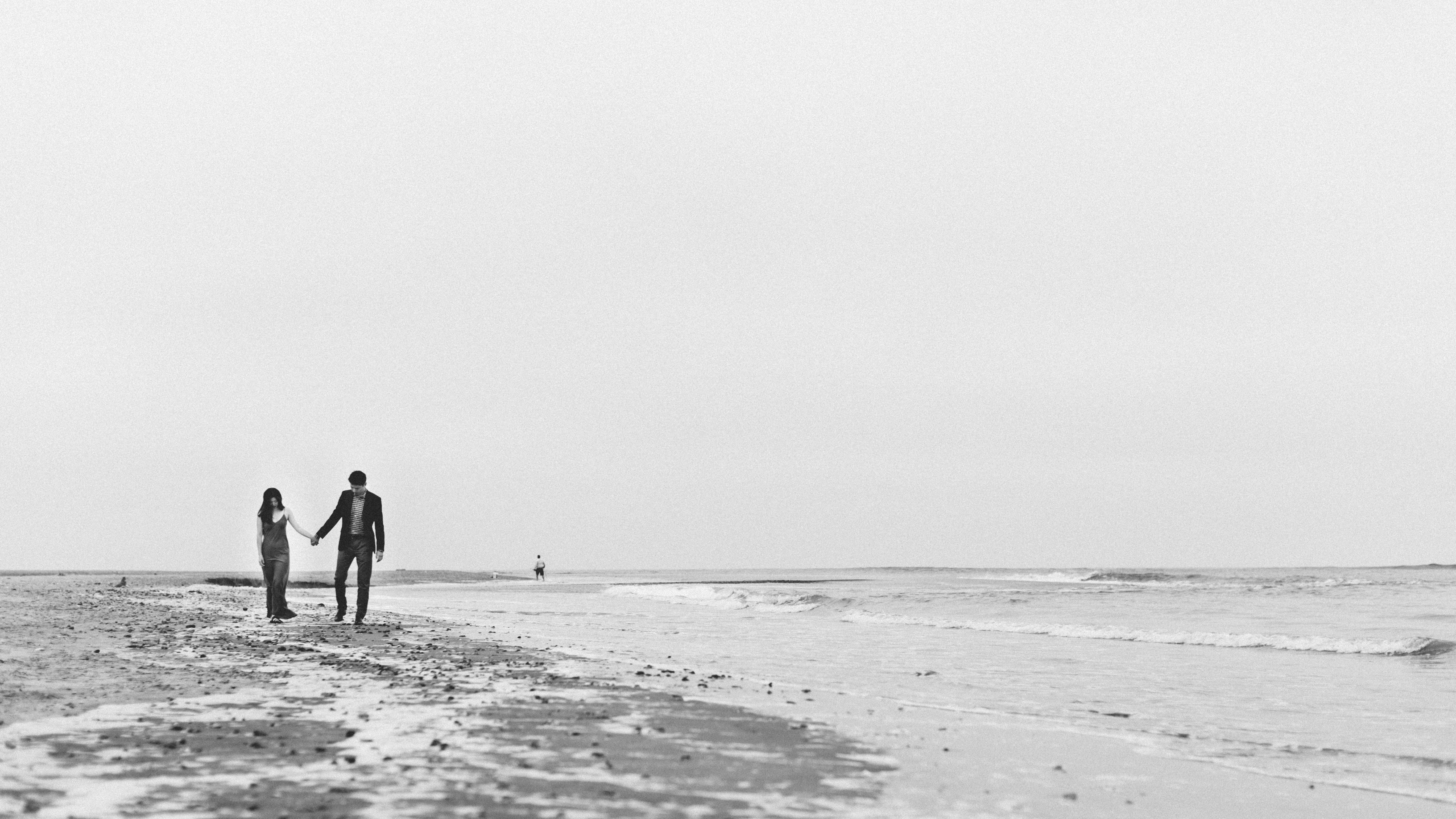 Couple holding hand while walking along the shore