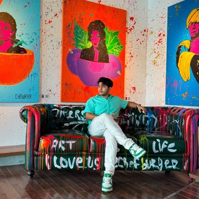 Modern red brick apartment or office building viewed from below against a blue sky, showcasing its geometric architecture with evenly spaced windows and balconies.