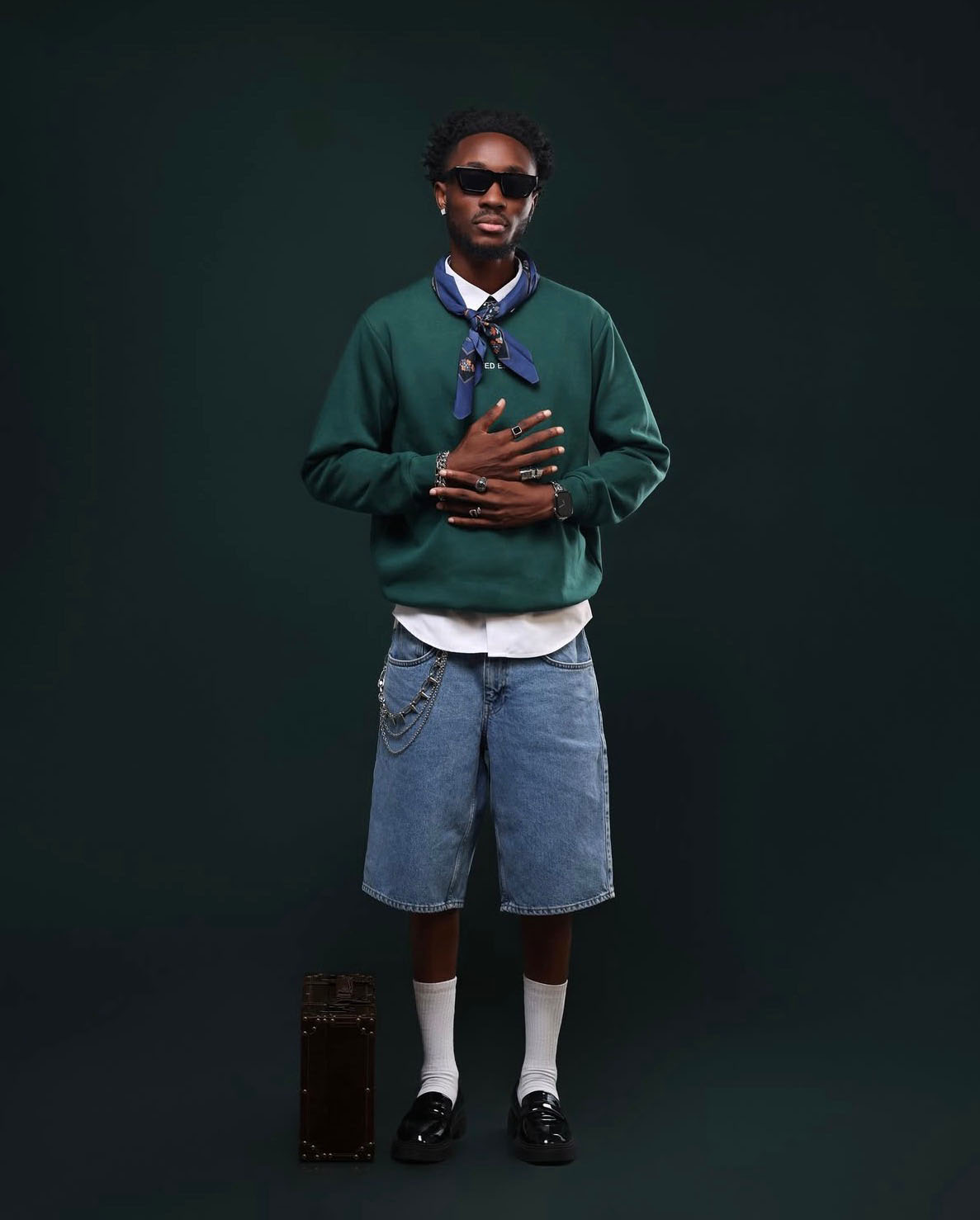 Full-body streetwear portrait on a dark teal background