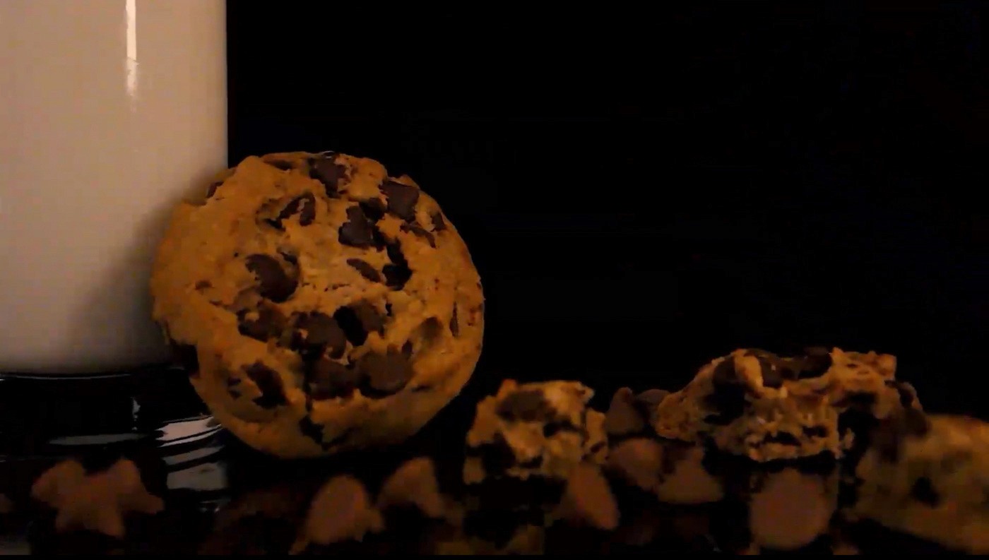 Milk and cookies surrounded by chocolate chips