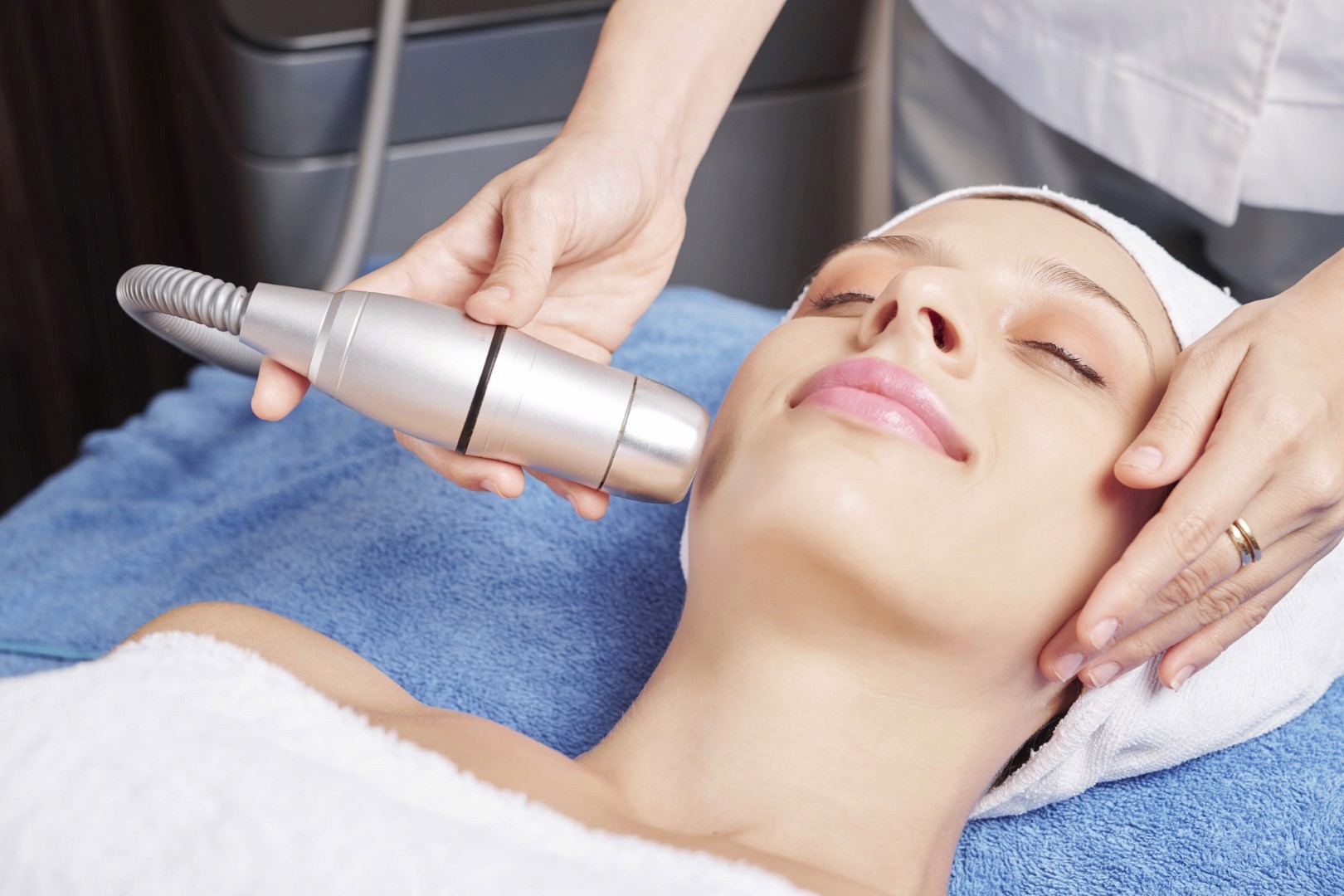 a woman laying on top of a bed holding a hair dryer