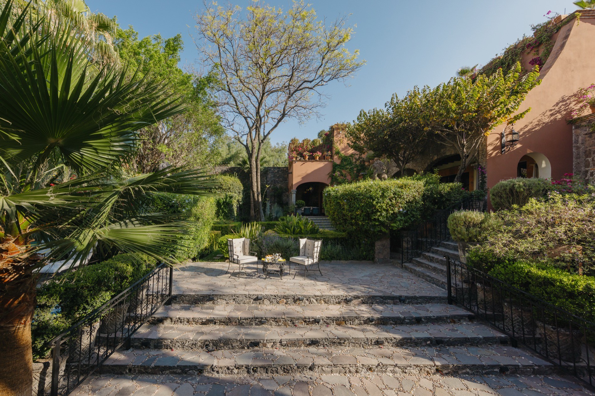 La Residencia San Miguel stone terrace garden with lounge seating, palm trees, and colonial walls