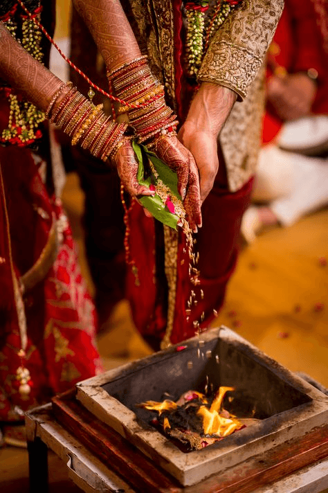 Traditional Indian wedding photography capturing a joyful moment during a Hindu wedding ceremony, with the bride and groom surrounded by family showering them with rose petals. Ideal for traditional wedding style photography inspiration.