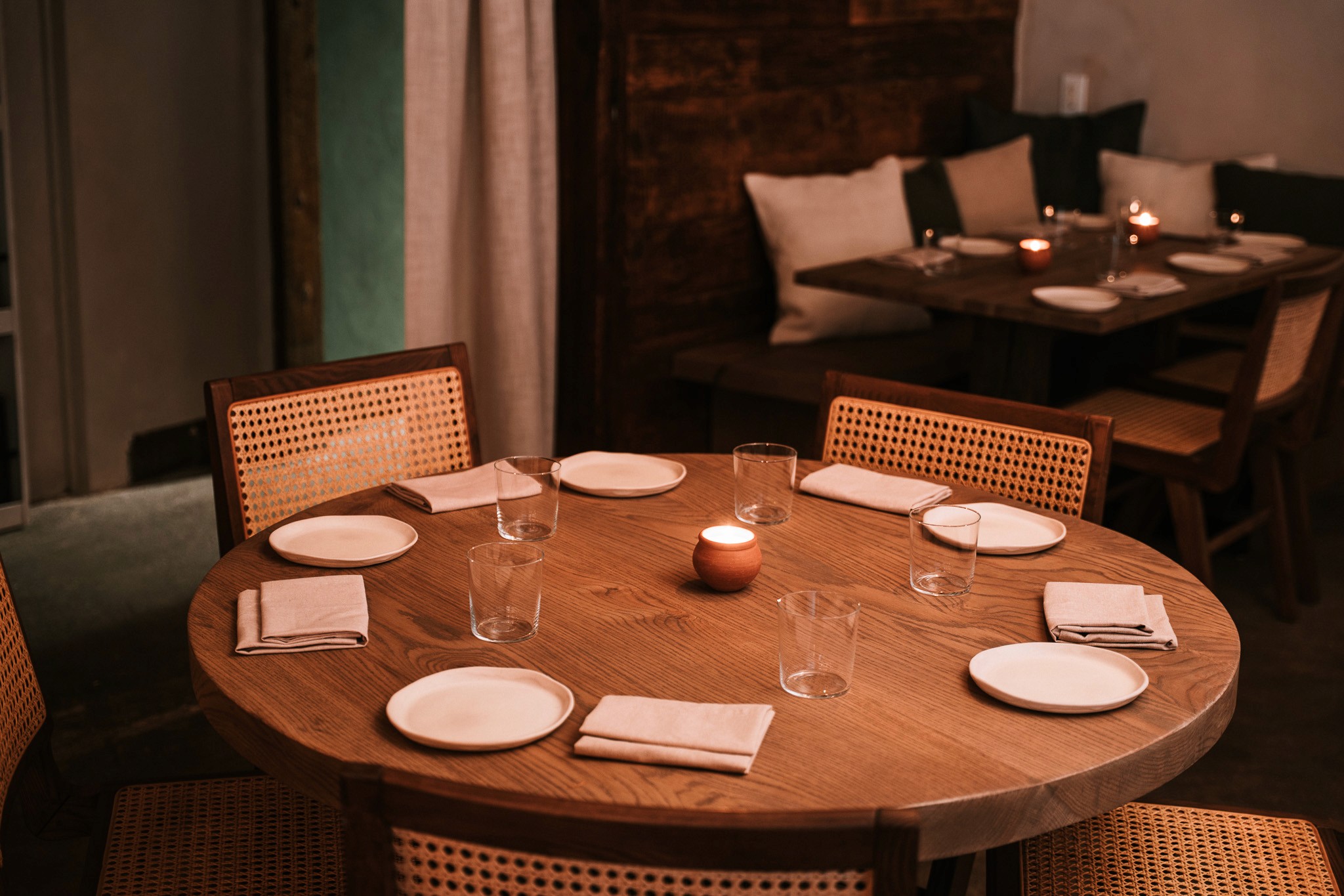 An empty table with plates, napkins, and glasses in a cozy environment
