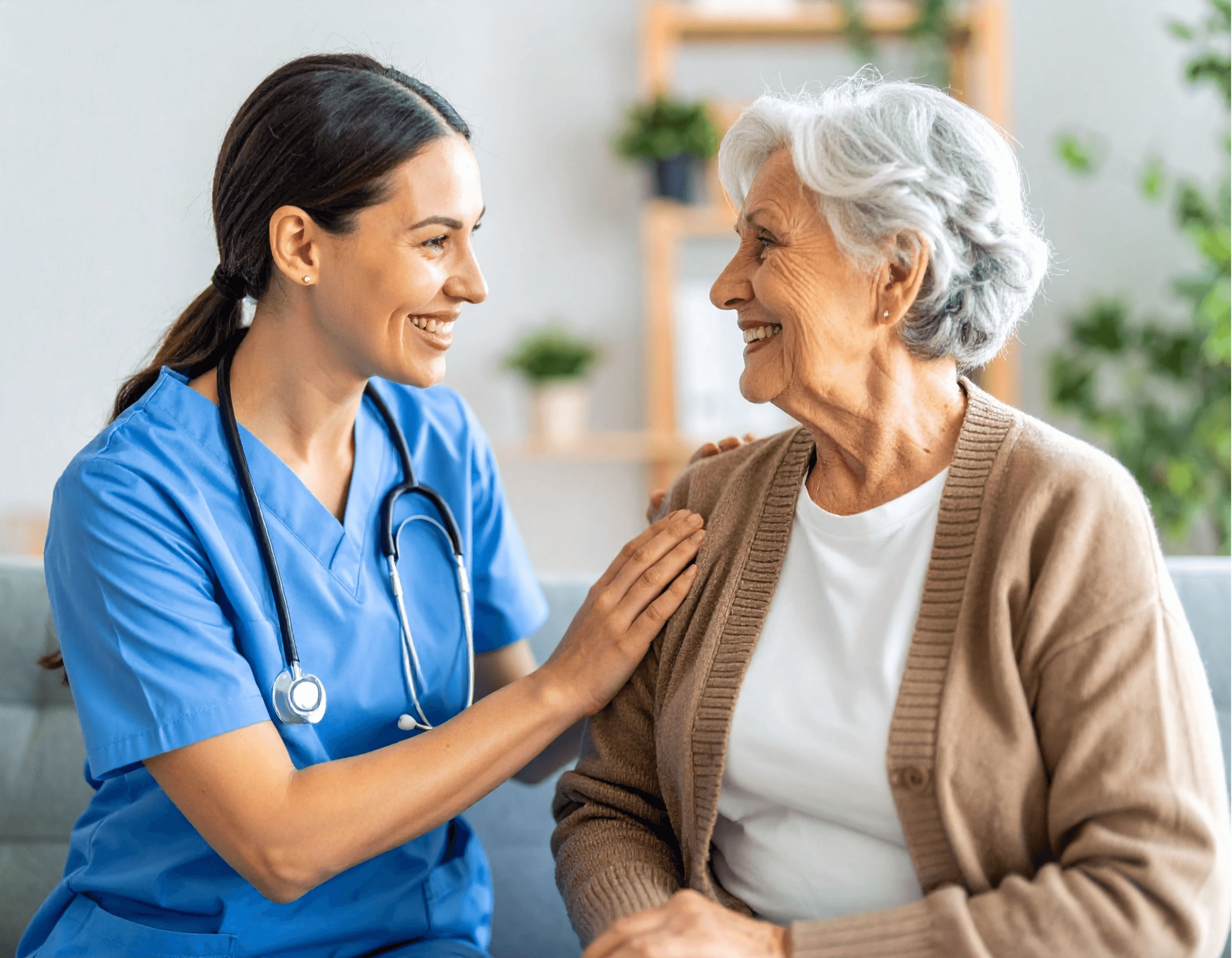 Caregiver smiling and supporting an elderly woman during an in-home care visit.