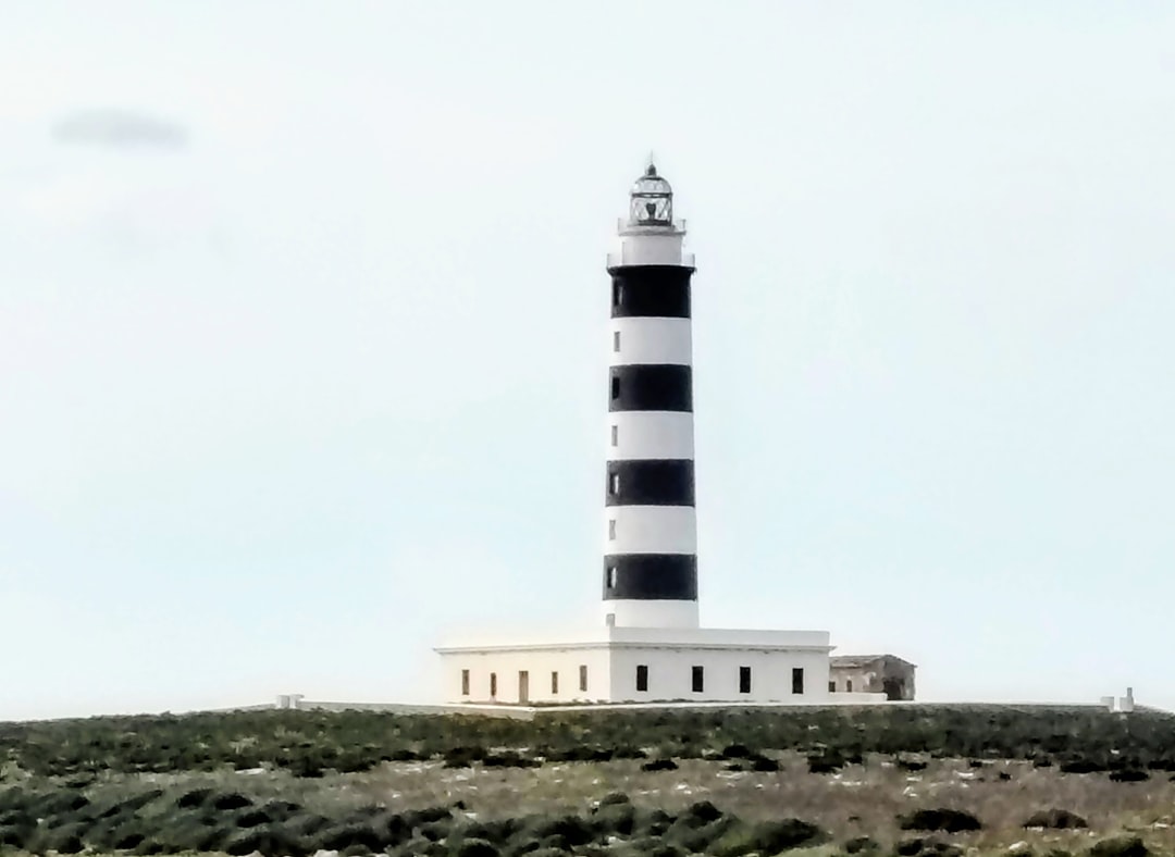 A solitary lighthouse against a gray sky, representing the coastal setting of the novels.