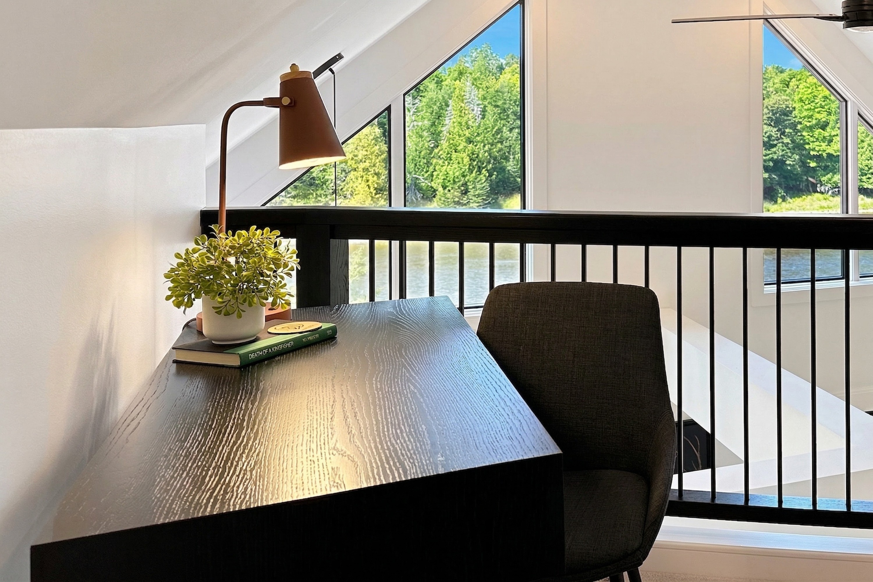Quiet upstairs writing desk beside loft railing and river views