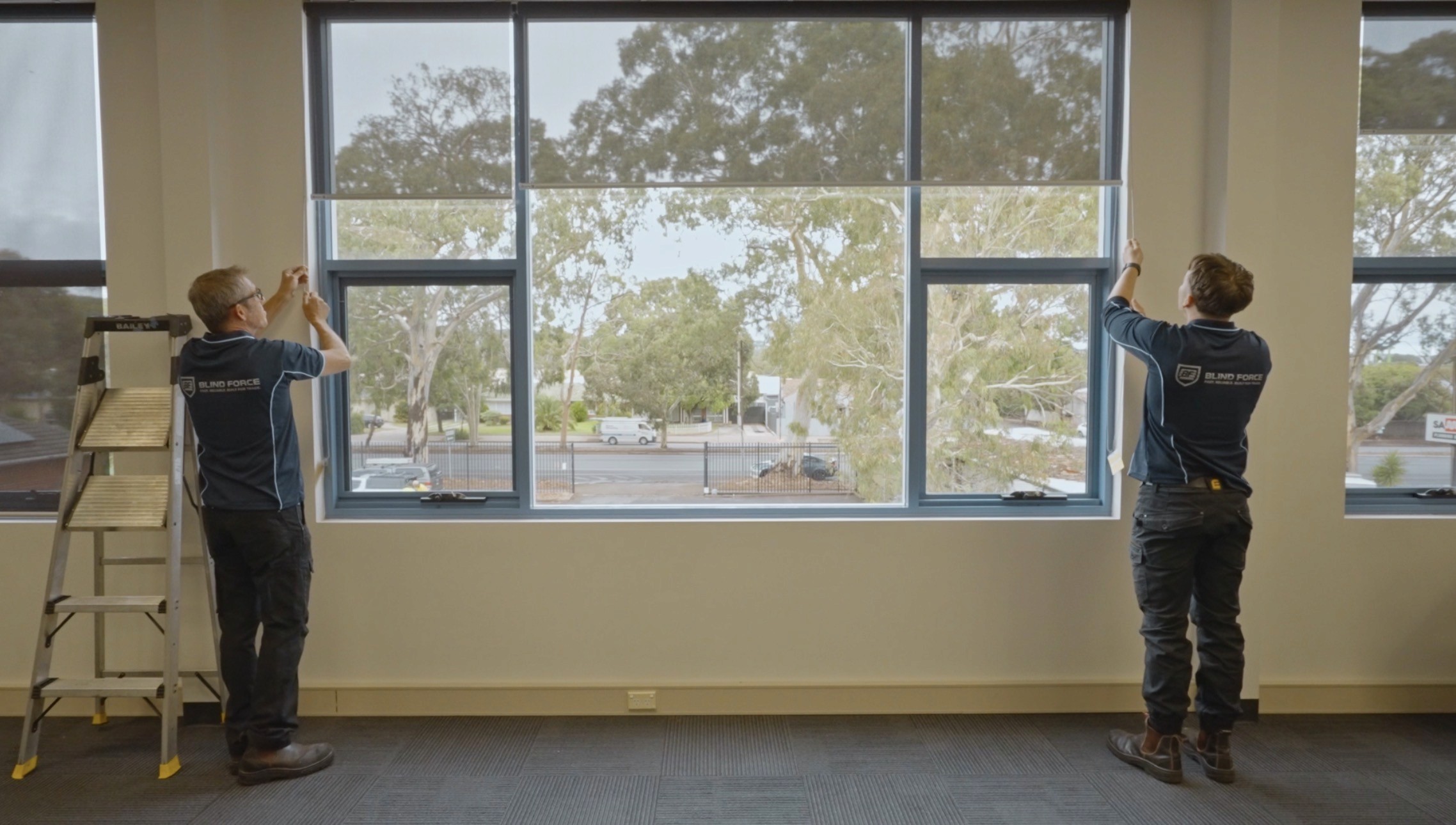 Two Blind Force technicians operating sheer roller blinds during installation
