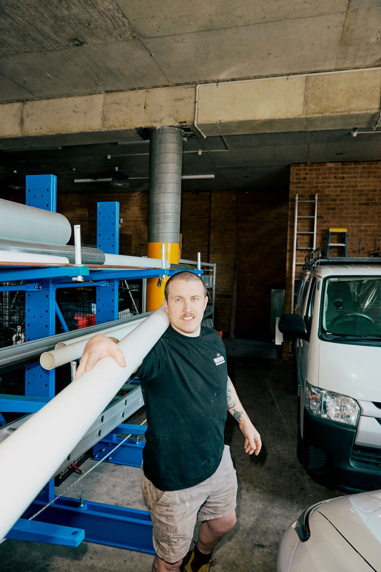 Plumber carrying PVC pipe inside the Good Maintenance warehouse.