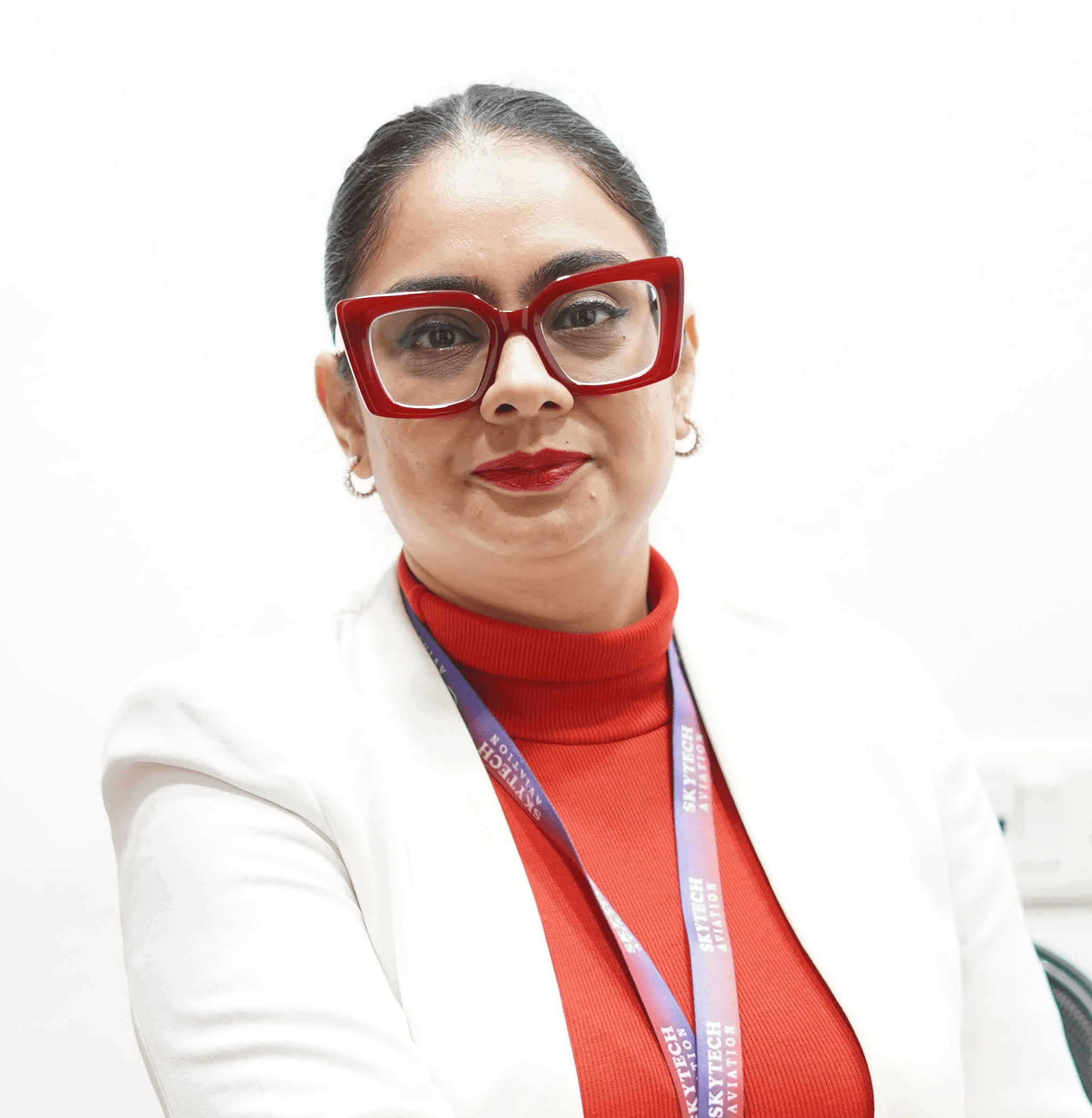 A woman in a white blazer sits at a desk.