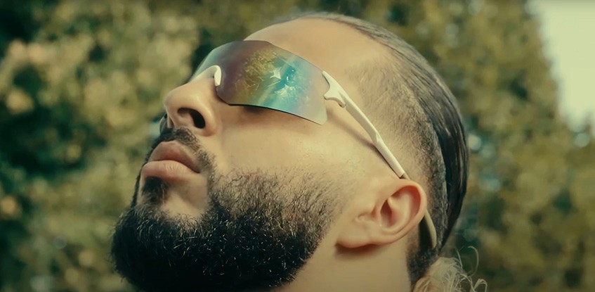 Dynamic scene from Ahmad Amin's 'TMAX' music video, featuring the artist performing energetically in front of a sleek, customized Yamaha TMAX scooter under vibrant city lights. A 9R Studios production, blending urban aesthetics with high-octane visuals to capture the essence of modern street culture